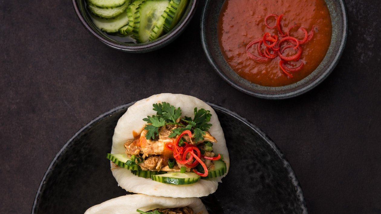 Nadýchaný bun plněný trhaným kuřecím masem s hoisin a chilli omáčkou, nakládanou okurkou, koriandrem a chilli Nadýchaný bun plněný trhaným kuřecím masem s hoisin a chilli omáčkou, nakládanou okurkou, koriandrem a chilli