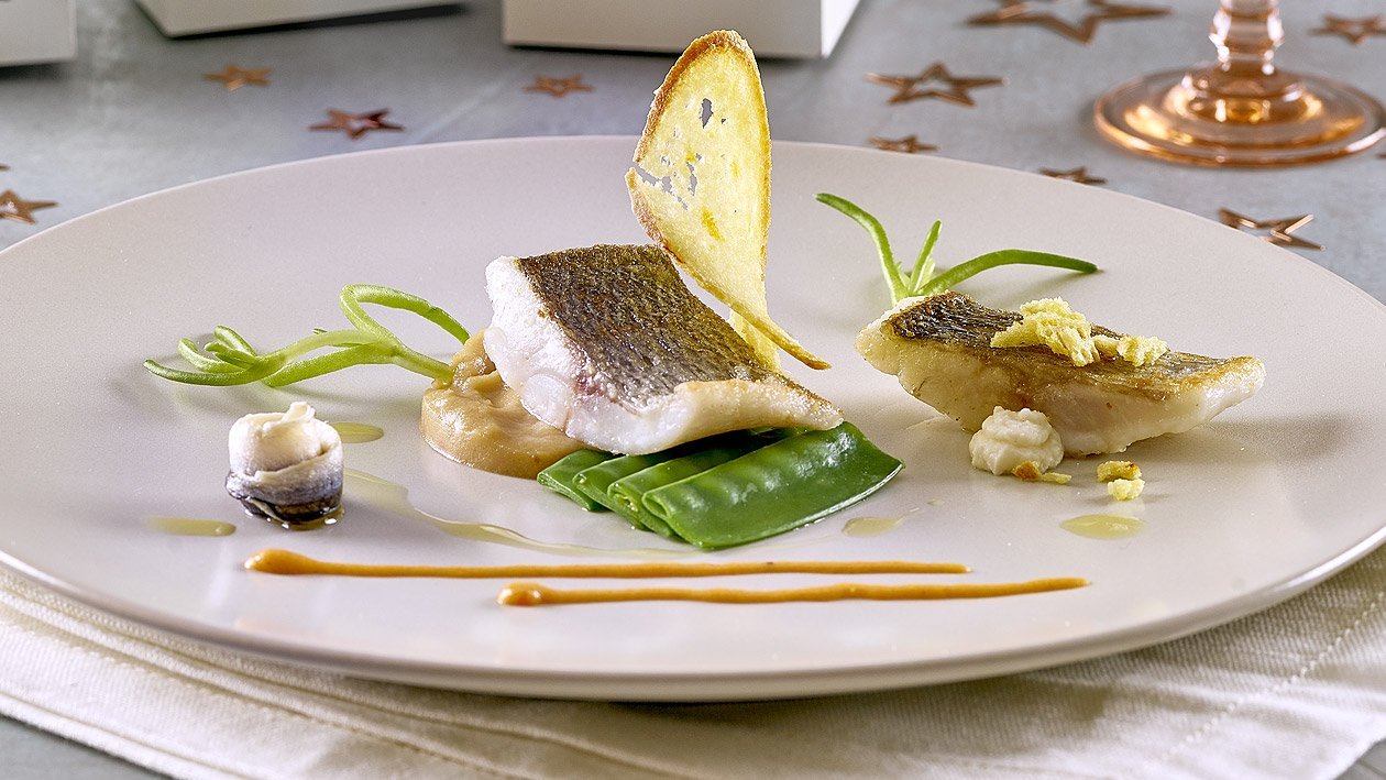 Gebratener Wolfsbarsch auf Bouillabaisse-Kartoffelpüree, Erbsenschotten, Rouille und eingelegeten Sardellen Gebratener Wolfsbarsch auf Bouillabaisse-Kartoffelpüree, Erbsenschotten, Rouille und eingelegeten Sardellen