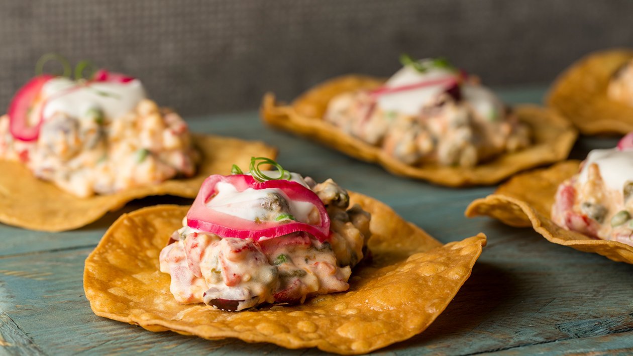 Ensaladilla vegana sobre taco frito, encurtidos y aceituna kalamata Ensaladilla vegana sobre taco frito, encurtidos y aceituna kalamata