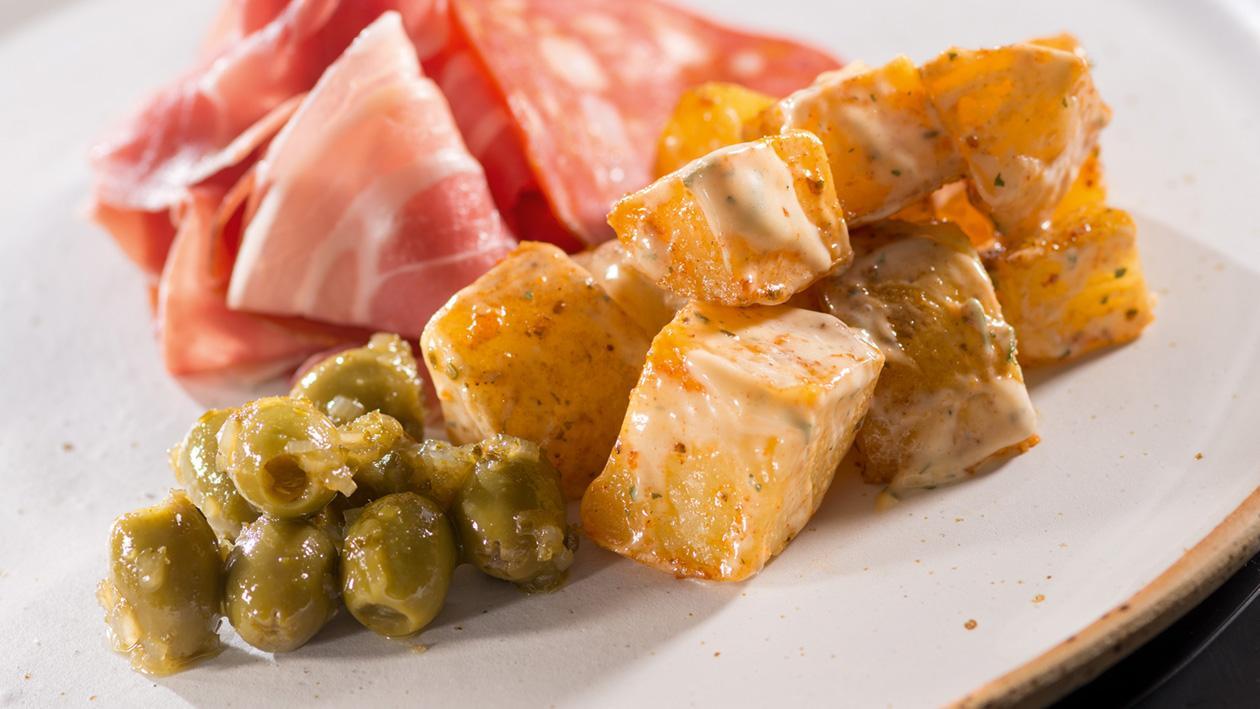 Tapas - Patatas Bravas z marynowanymi oliwkami i szynką Tapas - Patatas Bravas z marynowanymi oliwkami i szynką